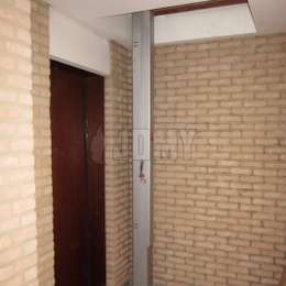 Compact and secured machine room access ladder Compact JOMY ladder used in a corridor for accessing a hatch to a machine room above.